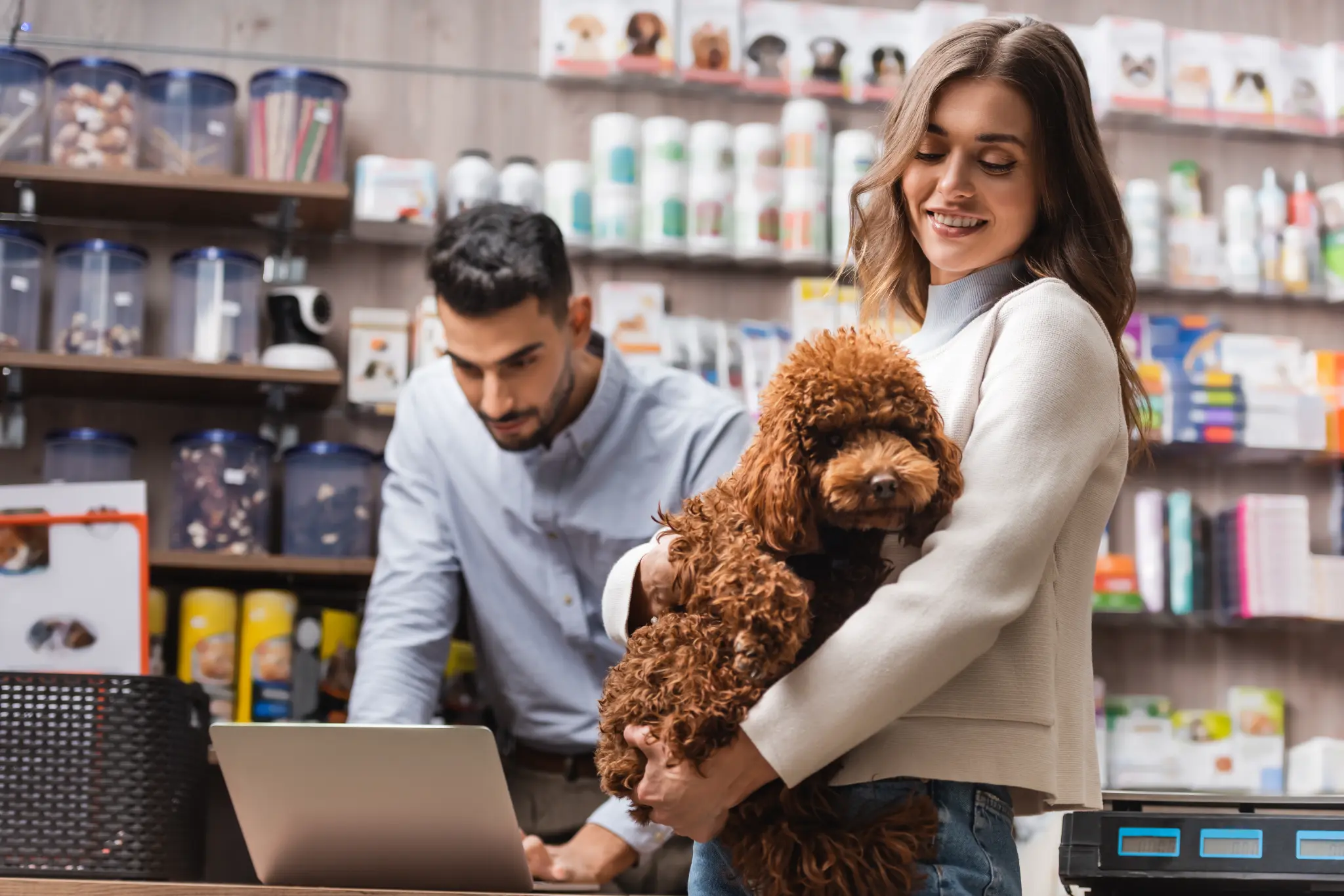 A woman holding a brown poodle in a pet shop — illustrative stock photograph.